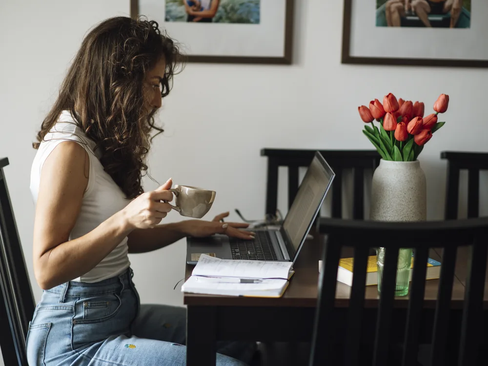 A person working on a laptop with a coffee in a tidy home workspace