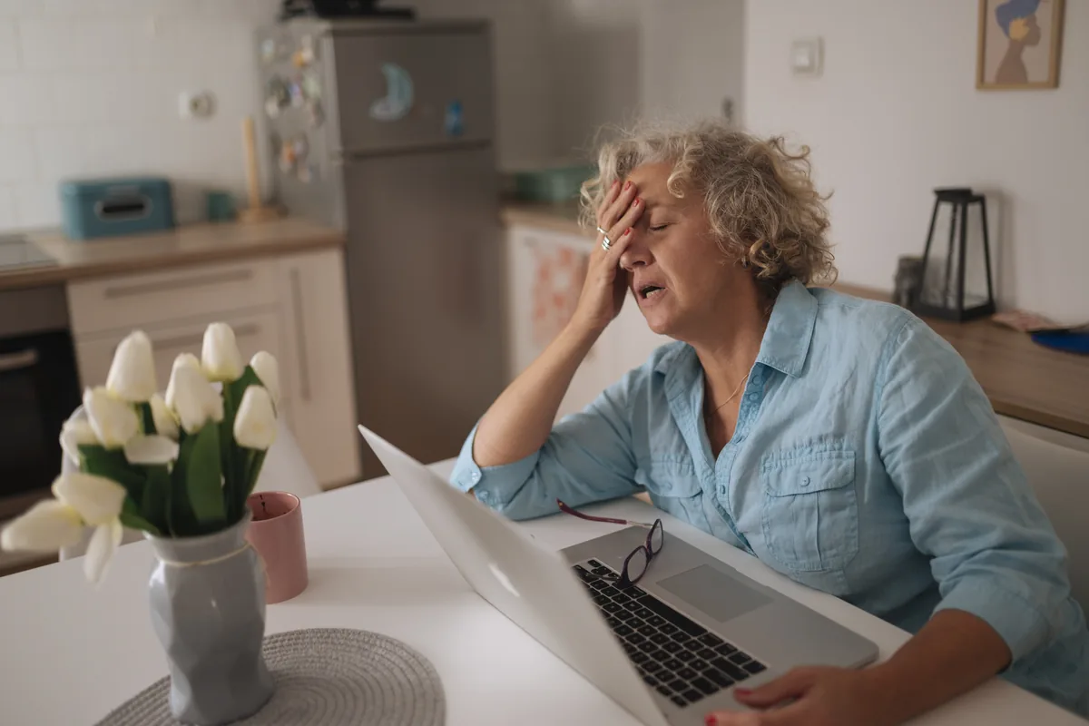 A person pausing with a concerned expression while at a laptop
