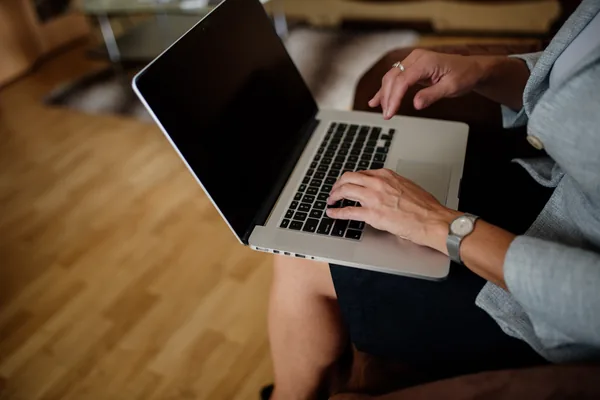 A person holding a laptop on their lap and typing
