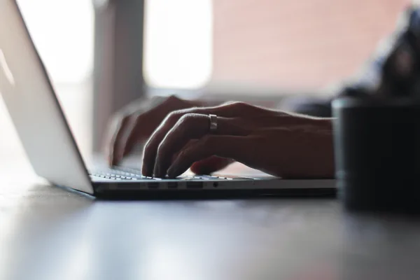 Overhead view of hands typing on a laptop keyboard