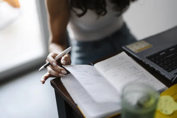 A person writing in a notebook while sitting at a desk